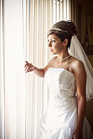 Bride standing beside window in wedding dress